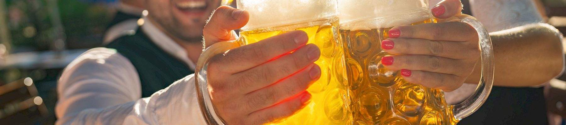People toasting with large mugs of beer outside.