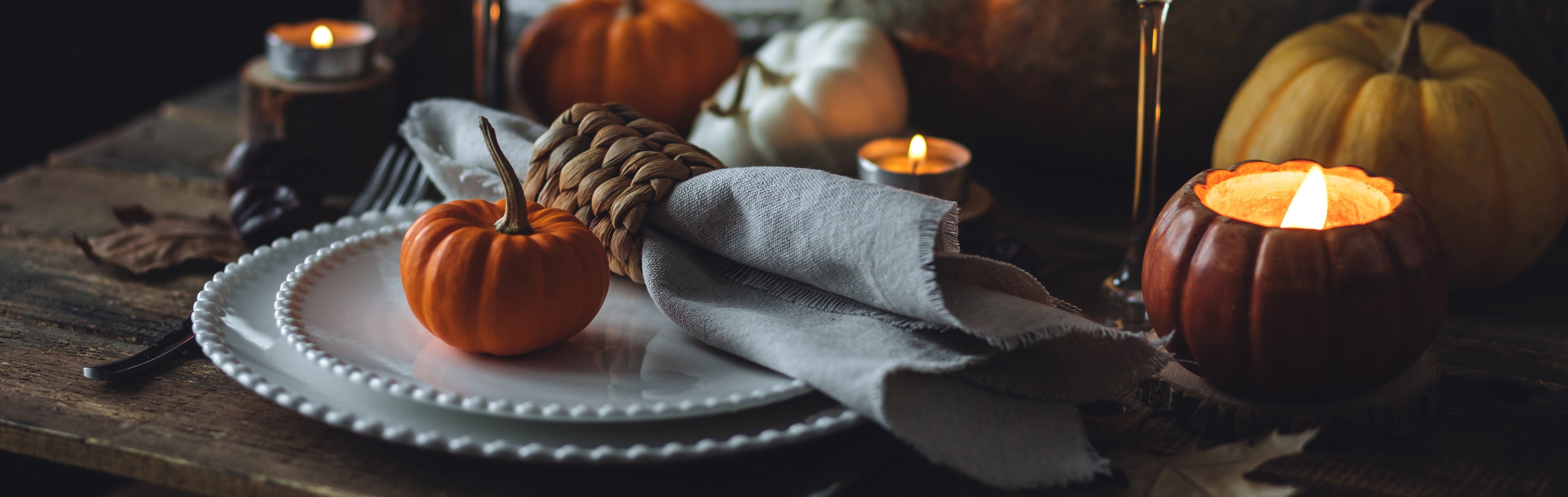 A fall-themed table setting with pumpkins and candles.