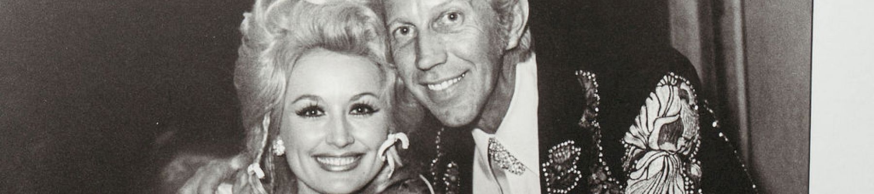 A black and white photo of three people smiling in a framed picture.