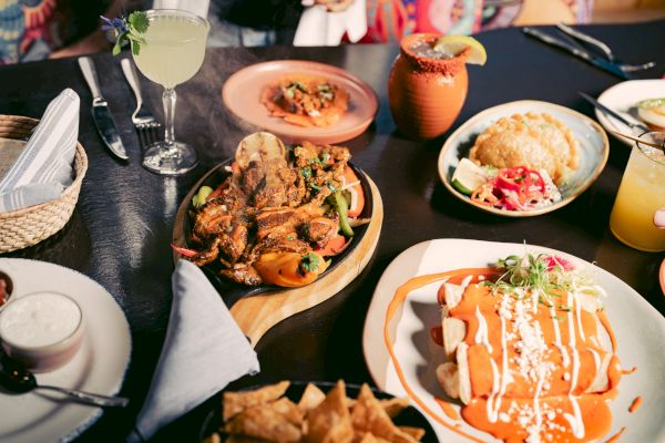 A table with various Mexican dishes, drinks, and utensils.