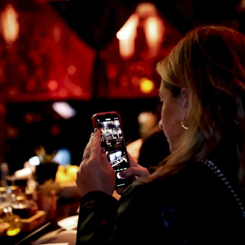 A person is taking a photo with a smartphone in a dimly lit setting.