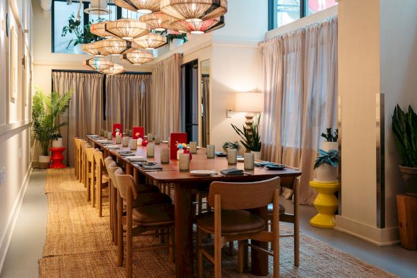 A dining room with a long table, chairs, and pendant lights.