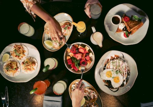 A variety of dishes including tacos, fruit, and drinks on a table.