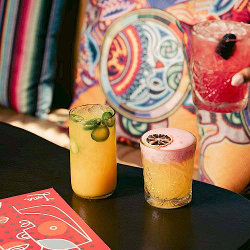 Colorful cocktails on a table with vibrant pillows in the background.