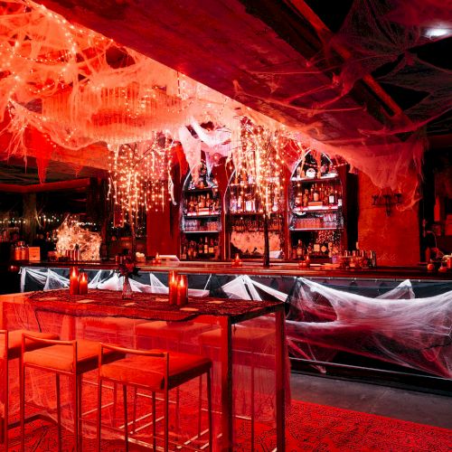 A bar decorated with red lighting and spider webs, creating a spooky atmosphere for Halloween.