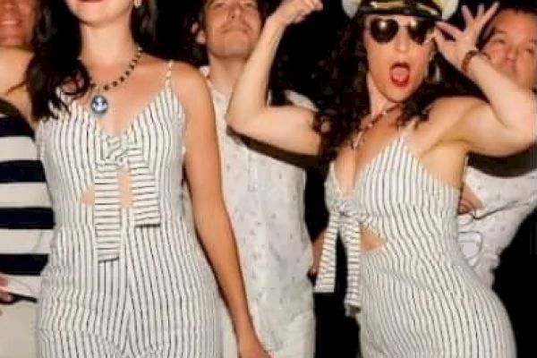 People in nautical-themed outfits and hats pose in a lively atmosphere, displaying a playful and stylish vibe.