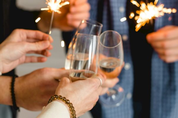 People holding sparklers and toasting with glasses, celebrating in a festive setting.