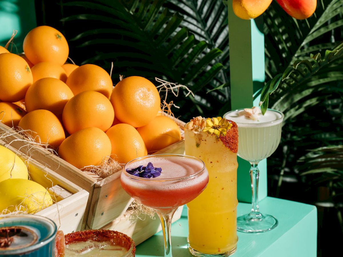 Various colorful cocktails and fruits on a vibrant, tropical-themed setup.