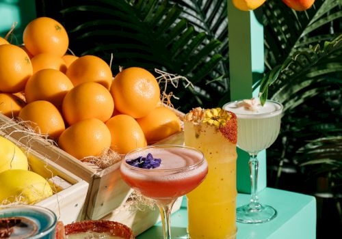 A display of colorful cocktails with fruit and greenery.