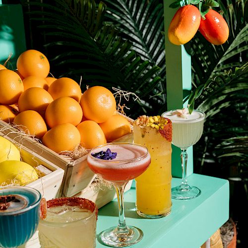 A display of colorful cocktails with fruit and greenery.