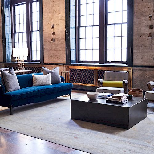 A stylish living room with a sofa, armchairs, lamps, and a coffee table.