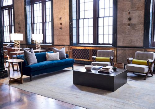 A stylish living room with a sofa, armchairs, lamps, and a coffee table.