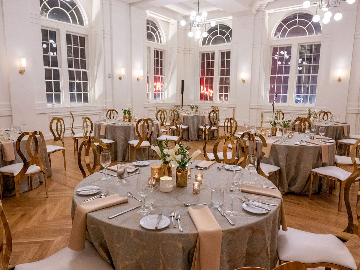 Elegant dining room with round tables, chairs, and place settings.