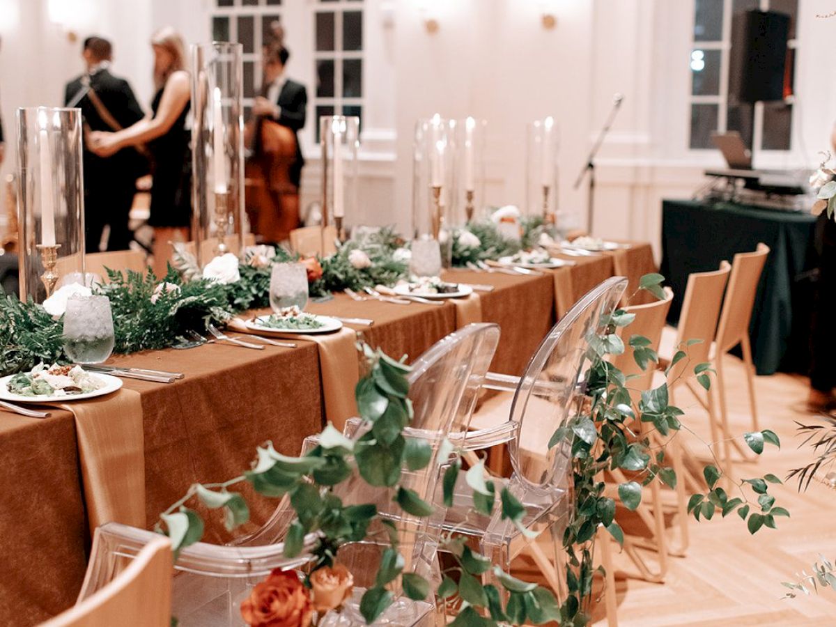 Elegant dining setup with floral decor and clear chairs in a bright room.