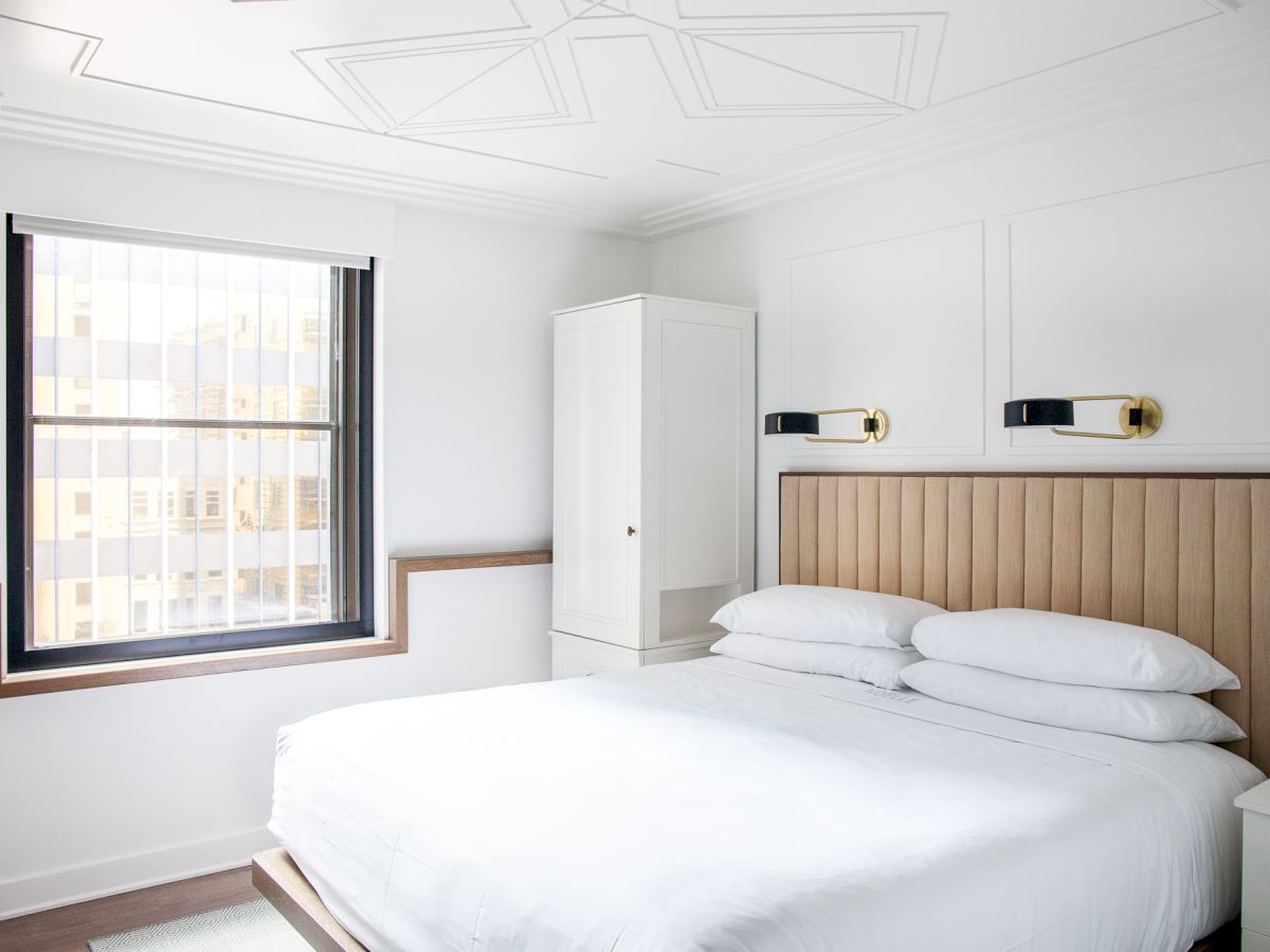 A modern bedroom with a bed, window, and cabinet.
