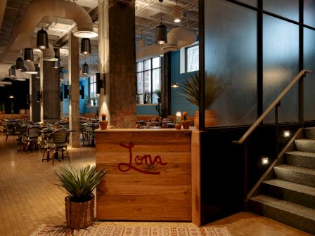A modern, industrial-style restaurant with wooden decor and dining tables.