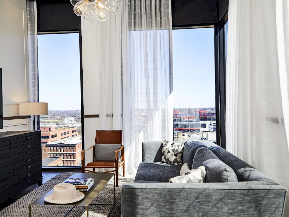 A modern living room with a sofa, chair, coffee table, and large windows.