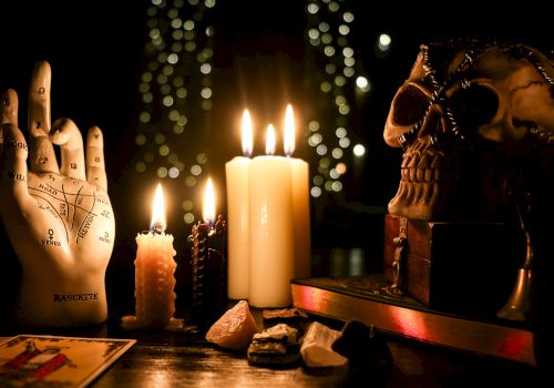 A mystical setup with candles, a skull, a palmistry hand, and crystals.