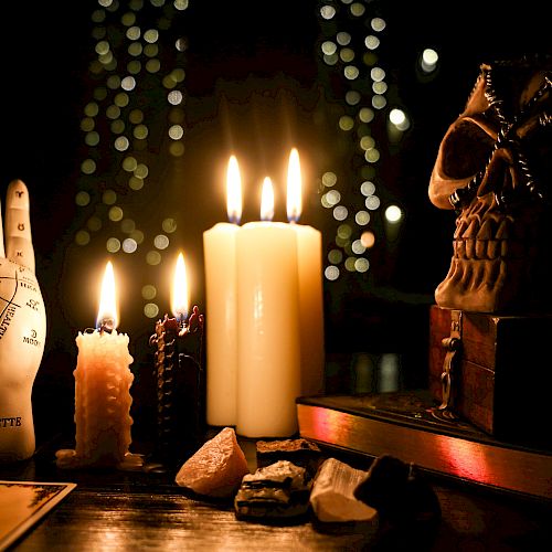 A mystical setup with candles, a skull, a palmistry hand, and crystals.