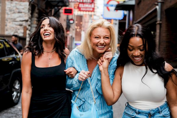 Three women happily walking and laughing together on a city street.