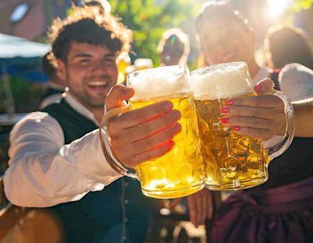 People toasting with large mugs of beer outside.