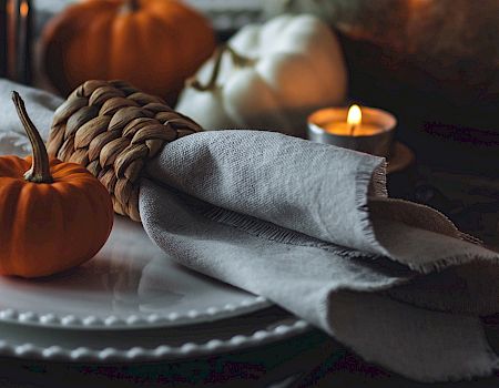 A fall-themed table setting with pumpkins and candles.