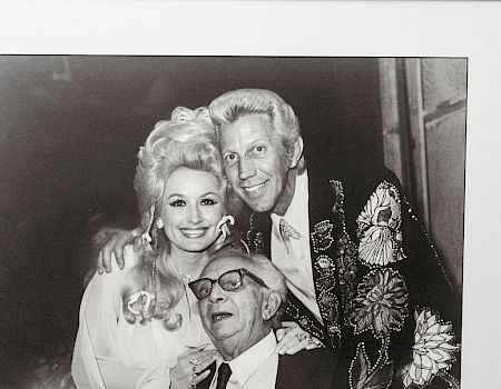 A black and white photo of three people smiling in a framed picture.